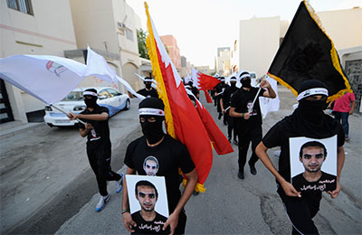 Masked protesters carry portraits of Ahmed Ismail Hassan at a demonstration in Salmabad village, south of Manama, Bahrain, April 10, 2013. (Reuters)
