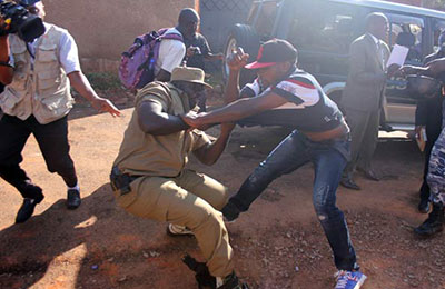 Police attempt to arrest a supporter of Erias Lukwago outside his home on December 2. (Monitor)
