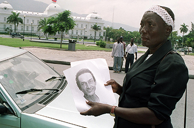 A Haitian woman hands out photographs of Jean Lépold Dominique, a journalist who was killed in 2000. (AFP/Thony Belizaire)
