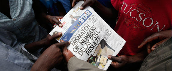 Les Kenyans lisent la couverture des élections dans le bidonville de Mathare à Nairobi, la capitale, le 9 Mars 2013. Une des raisons que les recettes publicitaires l'emportent sur les ventes de journaux en Afrique de l'Est est que plusieurs lecteurs se partagent un même exemplaire pour économiser de l'argent. (Reuters / Goran Tomasevic)