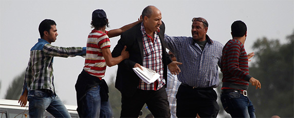 Сторонники движения "Братья Мусульмане" пытаются оттолкнуть журналиста, на снимке в центре, от полицейской академии на окрестностях Каира, где сверженный президент Мохаммед Мурси предстал перед судом 4 ноября 2013 года. По видимому ни в какой другой стране мира свобода прессы не ухудшилась так кардинально в 2013 года как в расколотом на лагеря Египте. (Reuters/Amr Abdallah Dalsh)