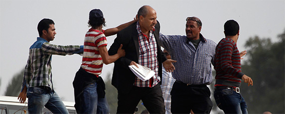 Supporters of the Muslim Brotherhood try to push a journalist, center, away from the police academy where ousted President Mohamed Morsi was on trial on the outskirts of Cairo, November 4, 2013. Perhaps nowhere did press freedom decline more dramatically in 2013 than in polarized Egypt. (Reuters/Amr Abdallah Dalsh)