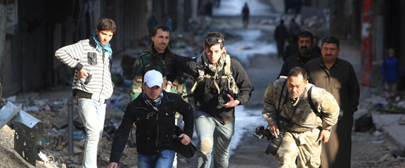 الصحفيان براين كرشة من كندا في الوسط وطشفمي فوجيموتو من اليابان على اليمين يهربان من الخطر مع مساعد صحفى مجهول الهوية في حي صلاح الدين في حلب في29  ديسمبر2012. (رويترز  مظفر سلمان)
