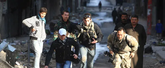 Journalists Bryn Karcha, center, of Canada, and Toshifumi Fujimoto, right, of Japan, run for cover with an unidentified fixer in Aleppo's district of Salaheddine on December 29, 2012. (Reuters/Muzaffar Salman)