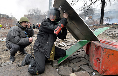 Protesters take cover amid clashes with police in Kiev on February 20. (AFP/Sergei Supinsky)