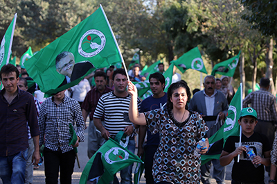 Kurdish people wave flags of Iraqi President and PUK leader Jalal Talabani during the September 2013 elections. (AFP/Ahmad al-Rubaye)