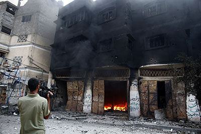 A journalist films a burning building in Gaza's Shijaiyah district on July 20. (AFP/Thomas Coex)