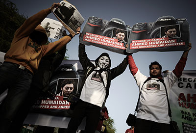 Bahraini photographers hold up placards in solidarity with freelance photojournalist Ahmed Humaidan, who was sentenced to 10 years in prison. (AFP/Mohammed al-Shaikh)