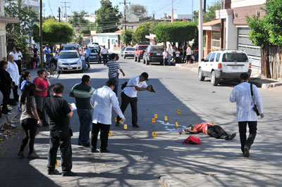 En esta foto del 12 de mayo del 2014, integrantes del equipo forense examinan el lugar donde una activista de un grupo de familiares de desaparecidos fue asesinada a tiros por pistoleros no identificados en la ciudad de Culiacán, México. (AP/El Debate, Dulce Mercado)
