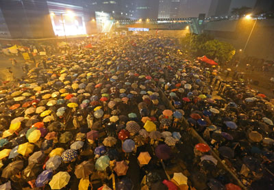 Pro-democracy protesters hold umbrellas under heavy rain in a street near the government headquarters in Hong Kong late on Tuesday, September 30. (AP)