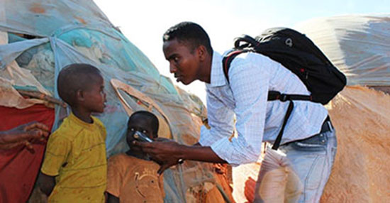 قُتل الصحفي الصومالي يوسف أحمد أبوكار بواسطة قنبلة وضعت في سيارته في عام 2014، ويظهر في الصورة وهو يتحدث لأطفال مشردين داخلياً. (عبد القادر أحمد)
