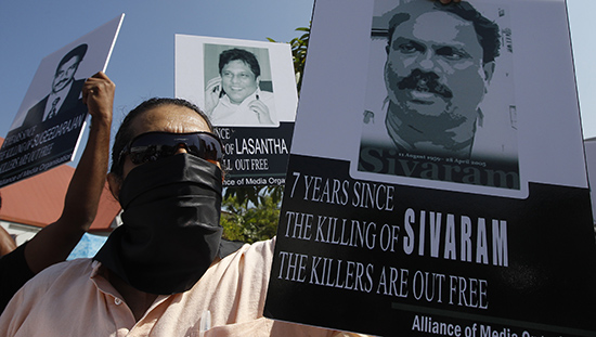 A member of the press holds a photo of Sri Lankan journalist Dharmeratnam Sivaram at a protest in 2013. Sivaram was abducted in April 2005 and found dead the next day. (Reuters/Dinuka Liyanawatte)