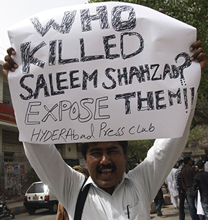 صحفي باكستاني يحمل لوحة تدعو إلى جلب قتلة سليم شهزاد إلى العدالة. وكان شهزاد الذي قُتل عام 2011 قد كتب قبيل مقتله عن وجود صلات مزعومة بين تنظيم القاعدة وسلاح البحرية الباكستاني. (أسيوشيتد برس/ برفيز مسيح)