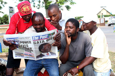 Taxi drivers read the news of President Michael Sata's death in The Post special edition on October 29, 2014 in Lusaka. (AFP/Chibala Zulu)