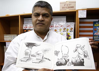 Zunar holds a copy of his banned cartoon book in 2010. The cartoonist has been arrested on accusations of sedition. (AP/Lai Seng Sin)