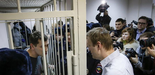 Алексей Навальный (справа) - российский оппозиционный лидер и блогер, борющийся против коррупции - беседует со своим братом, проходящим в качестве обвиняемого по тому же делу, за решёткой на скамье подсудимых во время судебного заседания в Москве 30 декабря 2014 года. (Рейтер/Сергей Карпухин)