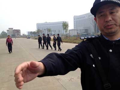 In this October 28, 2013, photo, a Chinese police officer reaches toward a journalist outside the courthouse where activists are on trial in Xinyu city, Jiangxi province. (AP/Aritz Parra)