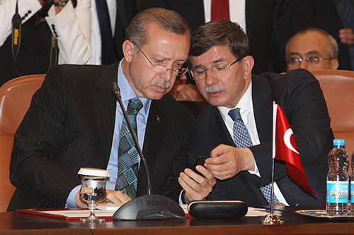 Recep Tayyip Erdoğan, left, looks at a cell phone during a meeting in 2013. Since Erdoğan became president there has been an increase in insult charges filed against Turkey's press. (AP/Abdeljalil Bounhar)