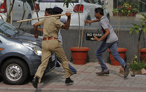 A policeman uses a baton to disperse protesters in Gujarat on August 25. Journalists were among those injured as police broke up the crowds. (AP/Ajit Solanki)