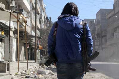 A young Syrian journalist carries a camera and a gun on February 9, 2014, in Aleppo. (AFP/Aleppo Media Center/Mohammed Wesam)