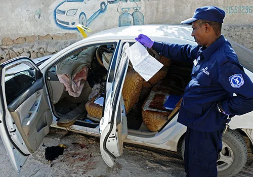 A security officer investigates the murder of Somali journalist Hindia Haji Mohamed, who was killed by a car bomb in December. (AFP/Mohamed Abdiwahab)