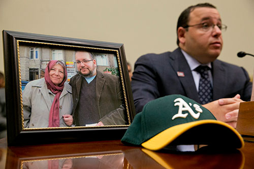 Ali Rezaian senta-se ao lado de uma foto mostrando seu irmão, o repórter do Washington Post Jason Rezaian, e sua mãe, durante uma audição do Comitê de Relações Exteriores para famílias com parentes presos no Irã. (AP / Jacquelyn Martin)