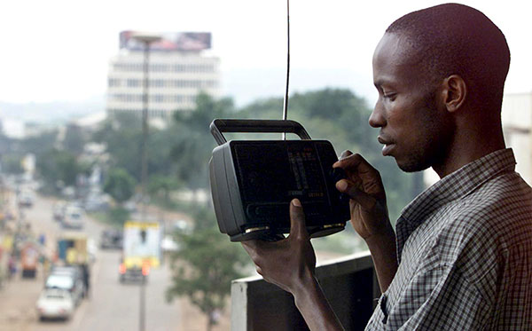 A man listens to the news on the radio in Kampala, August 16, 2003 (Reuters).