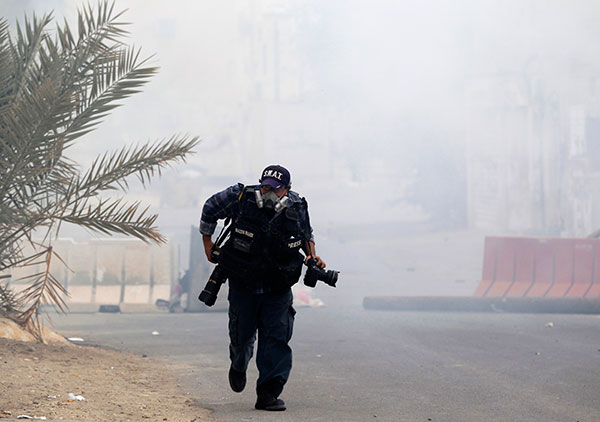 A photojournalist runs from tear gas at an anti-government protest in Bahrain, March 24, 2012. (Reuters/Ahmed Jadallah)