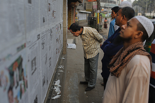 Bangladeshis read a newspaper pasted to a wall in Dhaka. The editor of The Daily Star, based in the city, is facing multiple legal cases after saying he published unsubstantiated reports several years ago. (AP/A.M. Ahad)