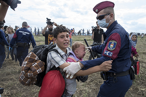 Hungarian police try to stop a young migrant with a baby in September 2015. Journalists covering the refugee story report being harassed, blocked and sometimes attacked. (Reuters/Marko Diurica)