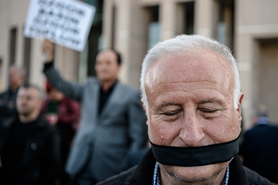 A protester covers his mouth outside the trial of two journalists from Cumhuriyet newspaper in Istanbul, April 1, 2016. (Ozan Kose/AFP)