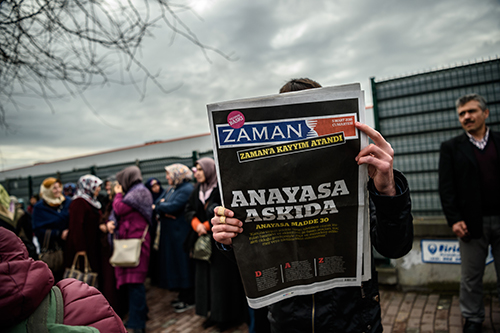 A copy of Zaman, with a headline that reads 'Suspended, the constitution,' is held up the day after the daily was taken over by court-appointed trustees. (AFP/Ozan Kose)