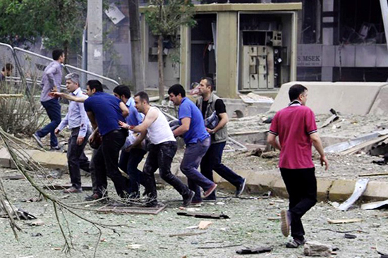 Onlookers help a man injured in a June 8, 2016, bombing in the southeastern Turkish town of Midyat that killed at least three people and injured at least 30 more. Residents attacked journalists filming the aftermath of the explosion. (AFP)