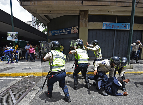 Las fuerzas de seguridad y residentes se enfrentan durante una protesta por la escasez de alimentos en Caracas el 2 de junio. Varios periodistas fueron atacados durante la protesta. (AFP/Juan Barreto)