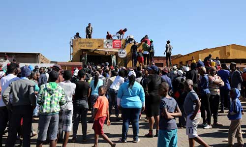 Locals try to gain access to a shop during protests in Atteridgeville, a township west of Pretoria, on June 21. Several reporters were attacked covering protests and looting this week. (Reuters/Siphiwe Sibeko)