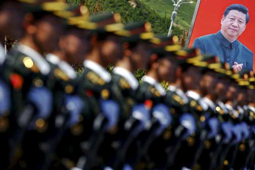 A picture of Chinese President Xi Jinping is seen behind People's Liberation Army soldiers in Beijing on August 22, 2015. (Reuters/Damir Sagolj)