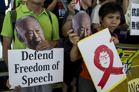Demonstrators protesting the trial of blogger Amos Yee hold pictures of the late Lee Kuan Yew, founder of modern Singapore, on July 5, 2015. (Reuters/Tyrone Siu)