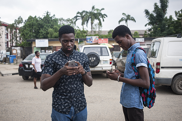 Two brothers use gaming apps on their smartphones in Lagos. Nigeria's new cybercrimes act has been used against at least five critical bloggers. (AFP/Stefan Heunis)