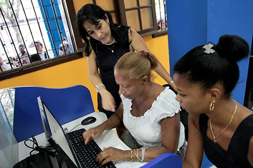 Un integrante del servicio proveedor de Internet, ETECSA, ayuda a clientes en un cibercafé de La Habana. El número de sitios de Wi-fi de acceso público han aumentado, pero los blogueros afirman que se necesitan más. (STR/AFP)