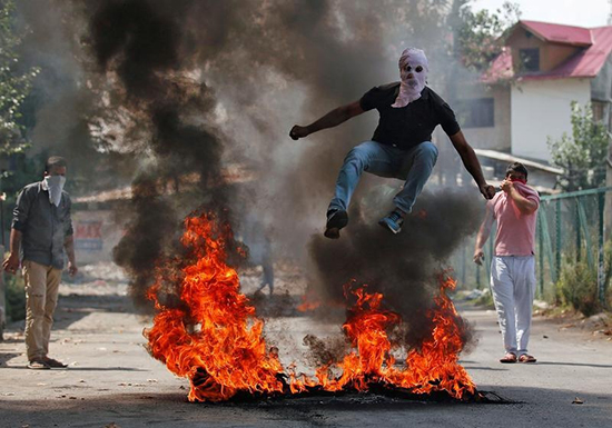 A protester jumps over burning debris in Srinagar, Jammu and Kashmir, September 12, 2016. (Reuters/Danish Ismail)