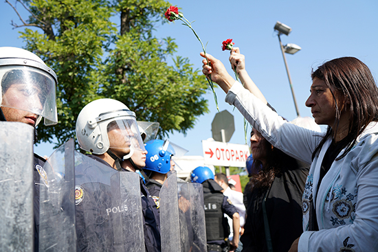 A demonstrator carrying a carnation to commemorate last year's bombing of a train station in Ankara meets a policeman in riot gear, October 10, 2016. (Reuters/Umit Bektas)