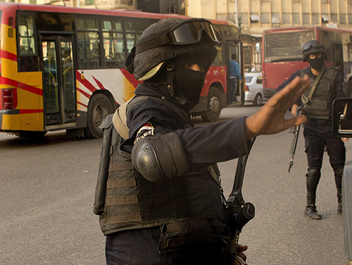 A masked policeman gestures to a photographer in Cairo ahead of planned protests on November 11. At least four journalists were detained covering areas where rallies were due to take place. (AP/Amr Nabil)