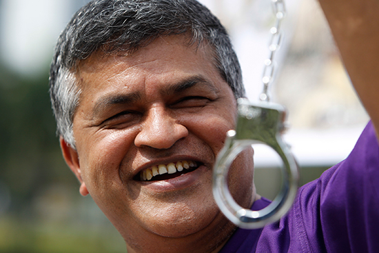 Cartoonist Zulkiflee Anwar Ulhauqe, better known as Zunar, poses in prison clothes with plastic handcuffs at a February 2, 2015, event launching a book in Petaling Jaya, Malaysia. (AP)