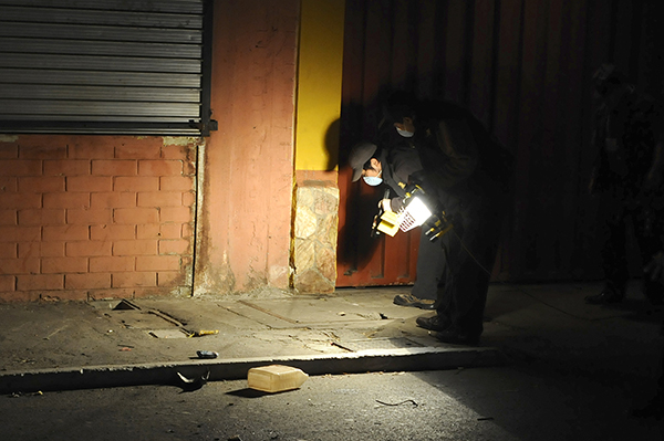 Funcionarios inspeccionan la escena de un crimen en Guatemala en 2013. Altos índices de criminalidad y violencia hacen difícil determinar si las víctimas son blanco de su labor periodística. (AFP/Johan Ordonez)