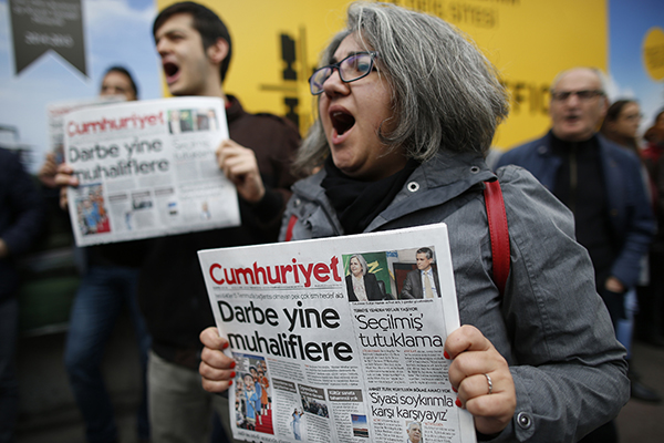 Люди, поддерживающие турецкую оппозиционную газету Cumhuriyet, протестуют возле офиса её редакции в Стамбуле против задержания полицией нескольких журналистов. (AP/Эмрах Гурель)