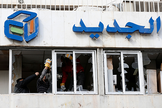 Workers remove broken glass from the windows of broadcaster Al-Jadeed's office in Beirut, February 15, 2017. Some 300 people attacked the building the previous night. (Reuters/Mohamed Azakir)