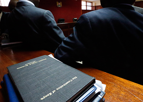 Lawyers confer on the floor of Kenya's High Court in Nairobi, next to a copy of the country's constitution, March 8, 2013. (Reuters/Steve Crisp)