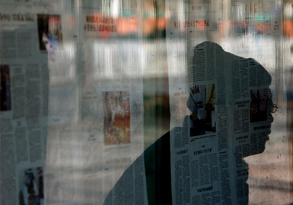 A passerby reads newspapers posted on a bulletin board in Beijing. Some foreign correspondents in China say they are finding it hard to find citizens willing to be interviewed. (AFP/Teh Eng Koon)