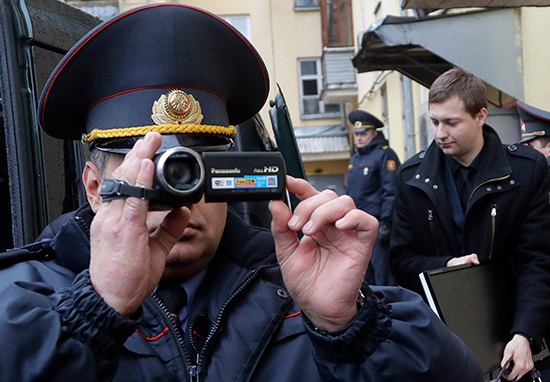 A Belarusian Interior Ministry official films journalists reporting on a police raid of one of Belsat TV's offices in Minsk, March 31, 2017. (AP/Sergei Grits)