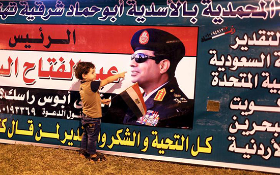 A child poses for a picture with a poster of Egyptian President Abdel Fattah el-Sisi in Cairo, August 6, 2015, as supporters cheered improvements to the Suez Canal.